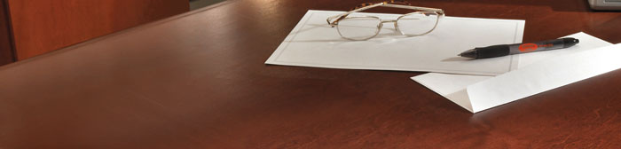 pair of glasses, pen and paper on a desk
